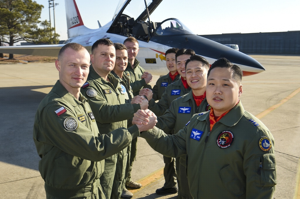 Pilots of the Air Forces of South Korea and Poland pose for a photo in front of a T-50 trainer aircraft at the South's 1st Fighter Wing in Gwangju, 329 kilometers south of Seoul, as the Polish service members begin their training to operate the FA-50 aircraft, in this photo provided by the South's armed service. (PHOTO NOT FOR SALE) (Yonhap)