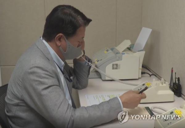 This file photo, provided by the unification ministry, shows a South Korean liaison officer talking to his North Korean counterpart at the Seoul bureau of their joint liaison office on Oct. 4, 2021. After a two-mo<em></em>nth suspension, the two Koreas restored cross-border communication lines that Pyo<em></em>ngyang suspended in protest against an annual combined military exercise of South Korea and the United States. (PHOTO NOT FOR SALE) (Yonhap)