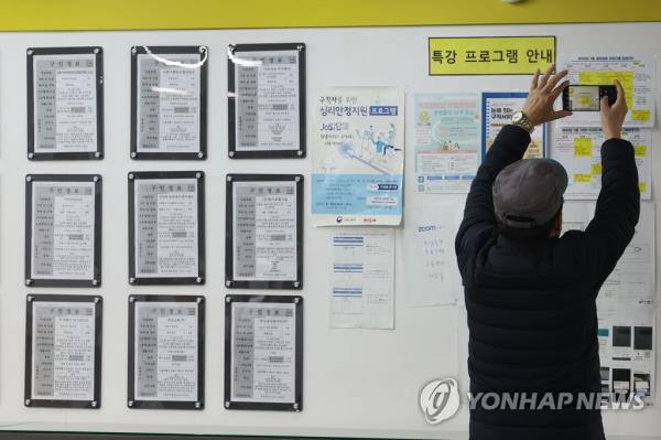 A jobseeker takes a photo of a notice board at a welfare center in western Seoul, in this file photo taken March 15, 2023. (Yonhap)