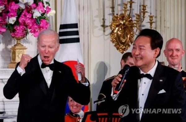 This photo distributed by Reuters shows U.S. President Joe Biden shouting while President Yoon Suk Yeol sings during a state dinner at the White House on April 26, 2023 (Yonhap)