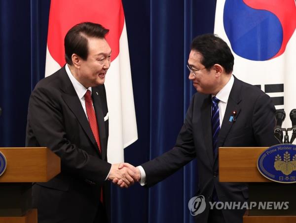 President Yoon Suk Yeol (L) shakes hands with Japanese Prime Minister Fumio Kishida at the end of their joint news co<em></em>nference after their summit in Tokyo on March 16, 2023. (Yonhap)