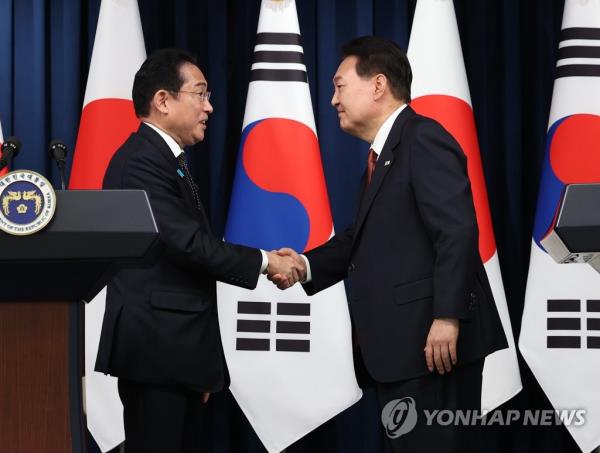 South Korean President Yoon Suk Yeol (R) and Japanese Prime Minister Fumio Kishida shake hands after holding a joint press co<em></em>nference at the presidential office in Seoul on May 7, 2023. During their talks, Yoon and Kishida agreed to allow a group of South Korean experts to visit Japan to inspect the planned release of radioactive water from the crippled Fukushima nuclear power plant. (Yonhap)