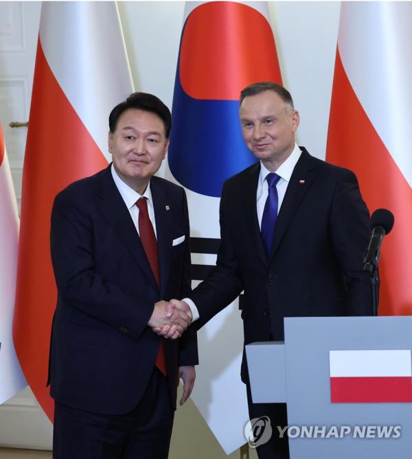 South Korean President Yoon Suk Yeol (L) and Polish President Andrzej Duda shake hands as they hold a joint press co<em></em>nference following their summit talks at the presidential palace in Warsaw on July 13, 2023. (Yonhap)