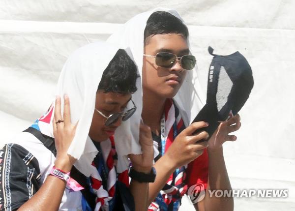 Scouts put towels on their heads at the o<em></em>ngoing World Scout Jamboree in Saemangeum, a<em></em>bout 200 kilometers southwest of Seoul, amid scorching heat on Aug. 4, 2023. (Yonhap)
