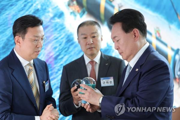 President Yoon Suk Yeol (R) looks at a battery precursor while listening to an explanation from LS Group Chairman Koo Ja-eun (C) ahead of a signing ceremony for LS Group's project to build a battery precursor plant, held at the Gunsan Saemangeum Co<em></em>nvention Center in Gunsan, 178 kilometers southwest of Seoul, in this photo provided by the presidential office. (PHOTO NOT FOR SALE) (Yonhap)