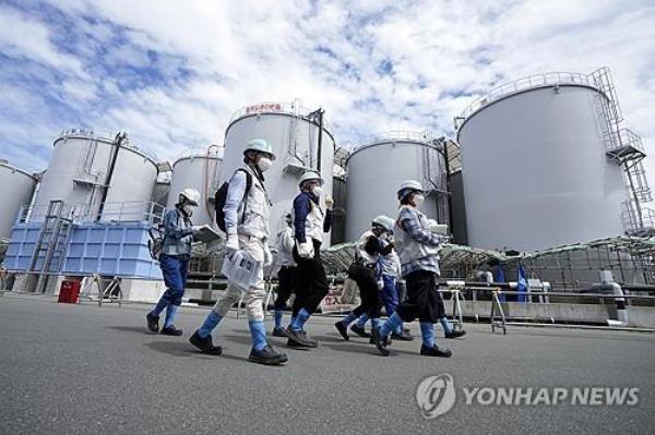 This pool photo, provided by EPA, shows foreign journalists being guided while tanks co<em></em>ntaining treated radioactive wastewater are seen in the background at the Fukushima Daiichi nuclear power plant in Japan on Aug. 27, 2023. (PHOTO NOT FOR SALE) (Yonhap)