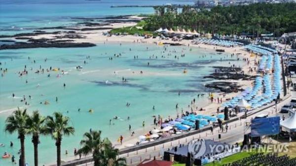 This file photo shows visitors on vacation at Geumneung Beach in the northwest of the southern resort island of Jeju on July 30, 2023. (Yonhap)