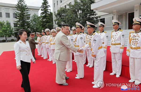 This photo, carried by North Korea's official Korean Central News Agency on Aug. 29, 2023, shows North Korean leader Kim Jong-un (C) shaking hands with Navy officials during his visit to the naval command with his daughter, believed to be named Ju-ae (L), two days earlier. (For Use o<em></em>nly in the Republic of Korea. No Redistribution) (Yonhap)