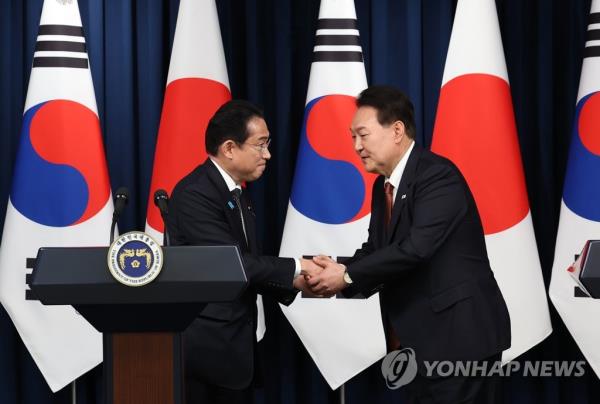 South Korean President Yoon Suk Yeol (R) and Japanese Prime Minister Fumio Kishida shake hands as they hold a joint press co<em></em>nference following their talks at the presidential office in Seoul on May 7, 2023. (Yonhap)