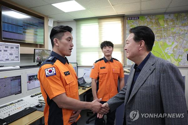 This photo provided by the presidential office on Sept. 30, 2023, shows President Yoon Suk Yeol (R) shaking hands with an on-duty firefighter at Jungbu Fire Station in Seoul during the Chuseok holiday. (PHOTO NOT FOR SALE) (Yonhap)