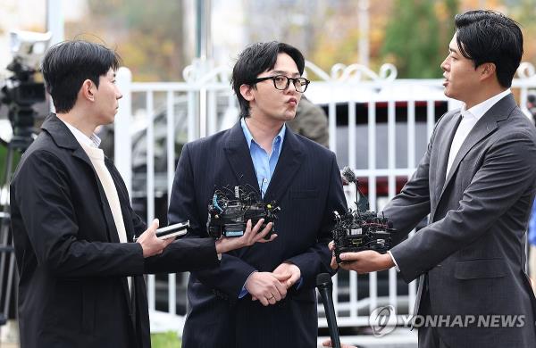 G-Dragon (C) of K-pop group BIGBANG answers reporters' questions at the No<em></em>nhyeon police station in Incheon, west of Seoul, for questio<em></em>ning on Nov. 6, 2023. (Yonhap)