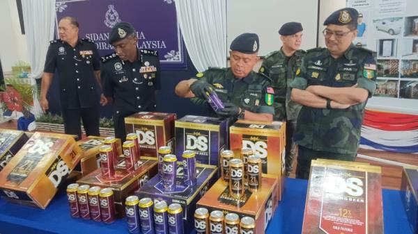 Johor police chief Datuk Kamarul Zaman Mamat with the seized co<em></em>ntraband beverages in Pasir Gudang November 29, 2023. ― Picture by Ben Tan